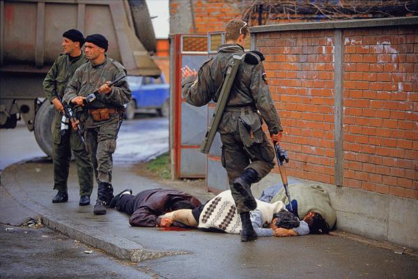 <br />
‎Bosnia, 1992. Miliziani serbi ‎delle “Tigri di Arkan” infieriscono sui corpi di civili musulmani appena trucidati, foto di Ron ‎Haviv.‎