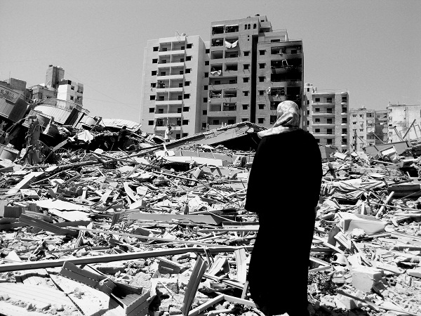 Beyrut ‎‎2006. Una donna davanti alle macerie di un palazzo distrutto dai bombardamenti israeliani. Foto ‎di Derek Henry Flood.‎<br />
