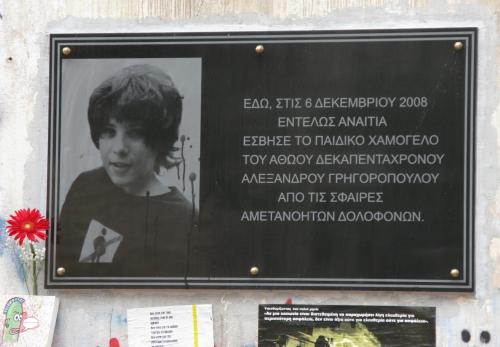 “Qui, il 6 dicembre 2008<br />
del tutto senza motivo<br />
è stato spento il sorriso di ragazzo<br />
del quindicenne innocente<br />
Alexandros Grigoropoulos<br />
dai proiettili<br />
di assassini insensati.”