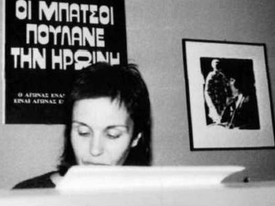 1978. Katerina Gogou legge una poesia. Alle sue spalle, un manifesto con la scritta: "GLI SBIRRI SPACCIANO EROINA".
