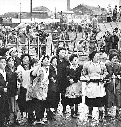 Miners' wives with arms linked form a picket line in front of the Miike mine to prevent second union miners from resuming production, April 20, 1960. Women were often put on the front lines in an effort to deter beatings by right-wing thugs.