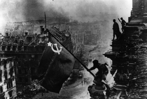 Una fotografía histórica: los soldados soviéticos levantan la bandera roja sobre el Reichstag y las ruinas de Berlín.